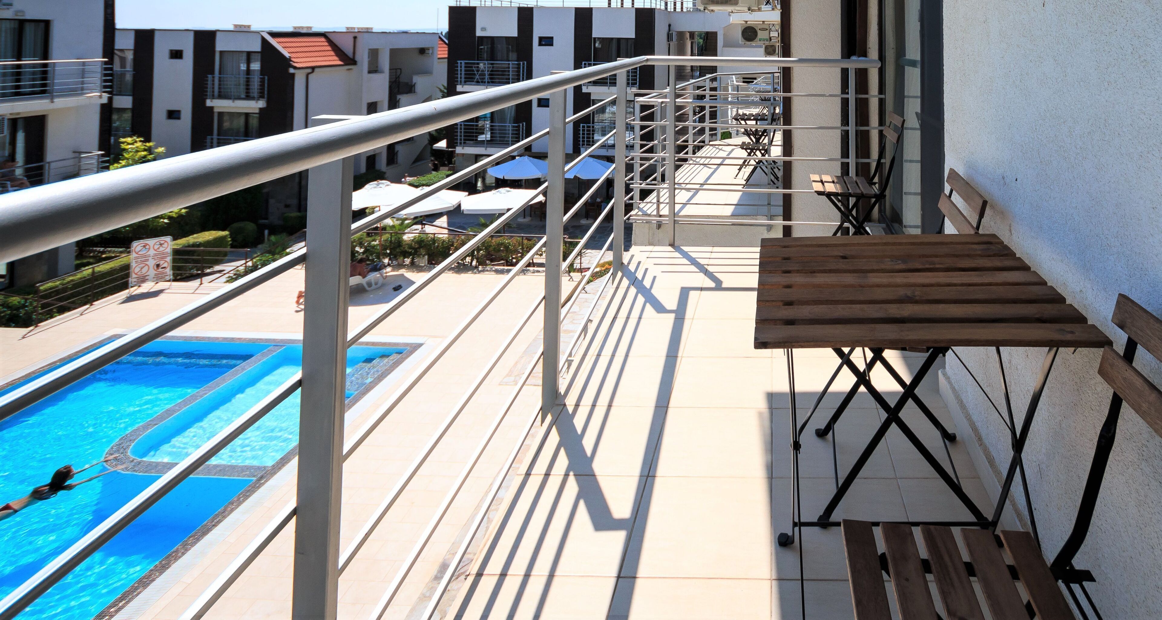 Un balcón con piscina, mobiliario exterior y vistas de los edificios circundantes.