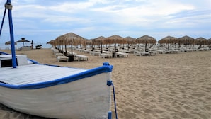 A beach with rows of white lounge chairs and thatched umbrellas. - New Line Village Apartments (Sunny Beach)