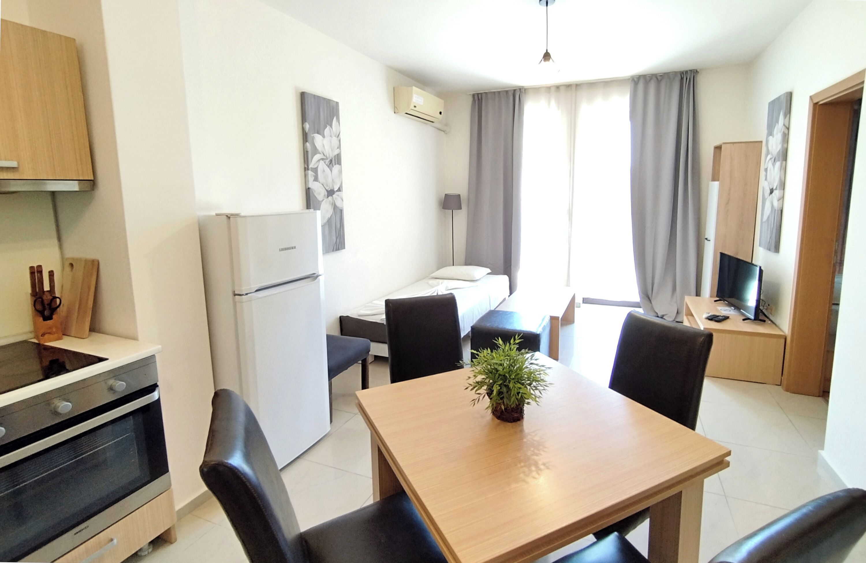 A compact kitchen with a refrigerator, oven, and a dining area with a table and chairs.