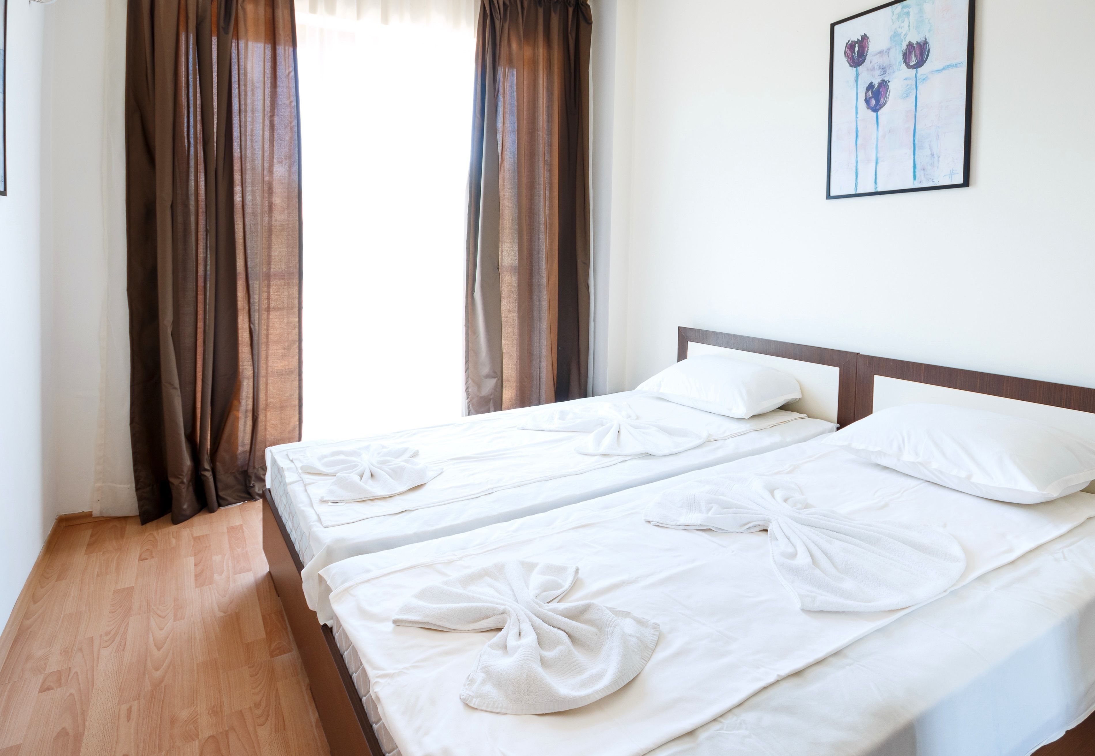 A hotel room with two beds, each with a neatly folded towel and a pillow.