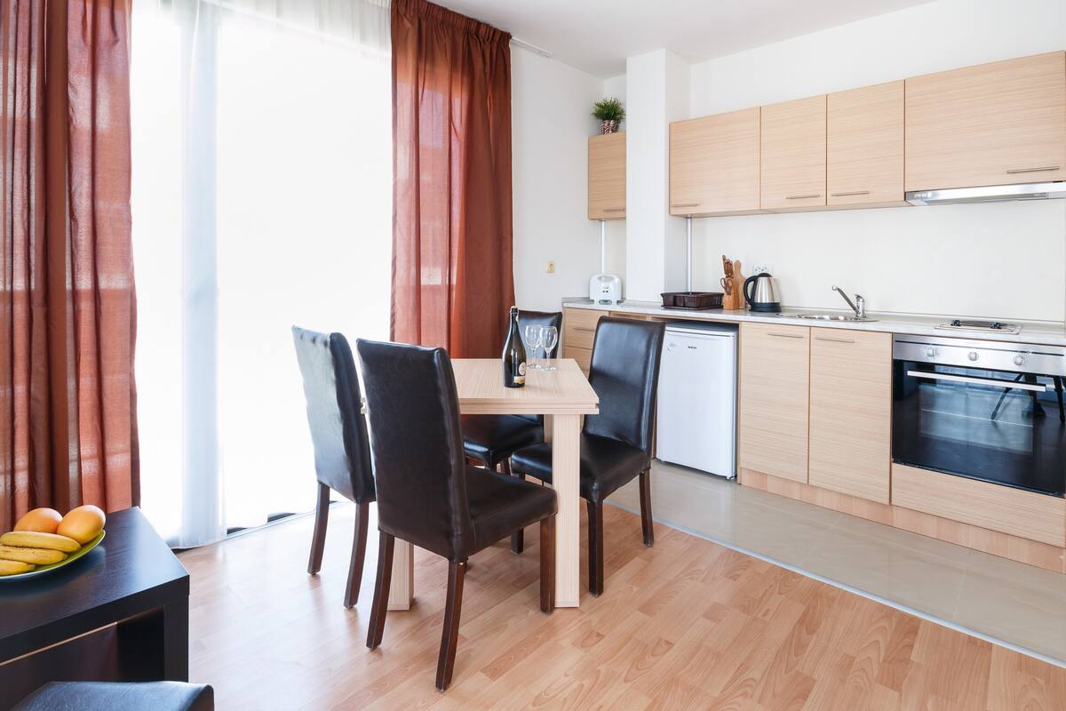 A modern kitchen with wooden cabinets, a dining table with chairs, and a small dining area with a table and chairs.