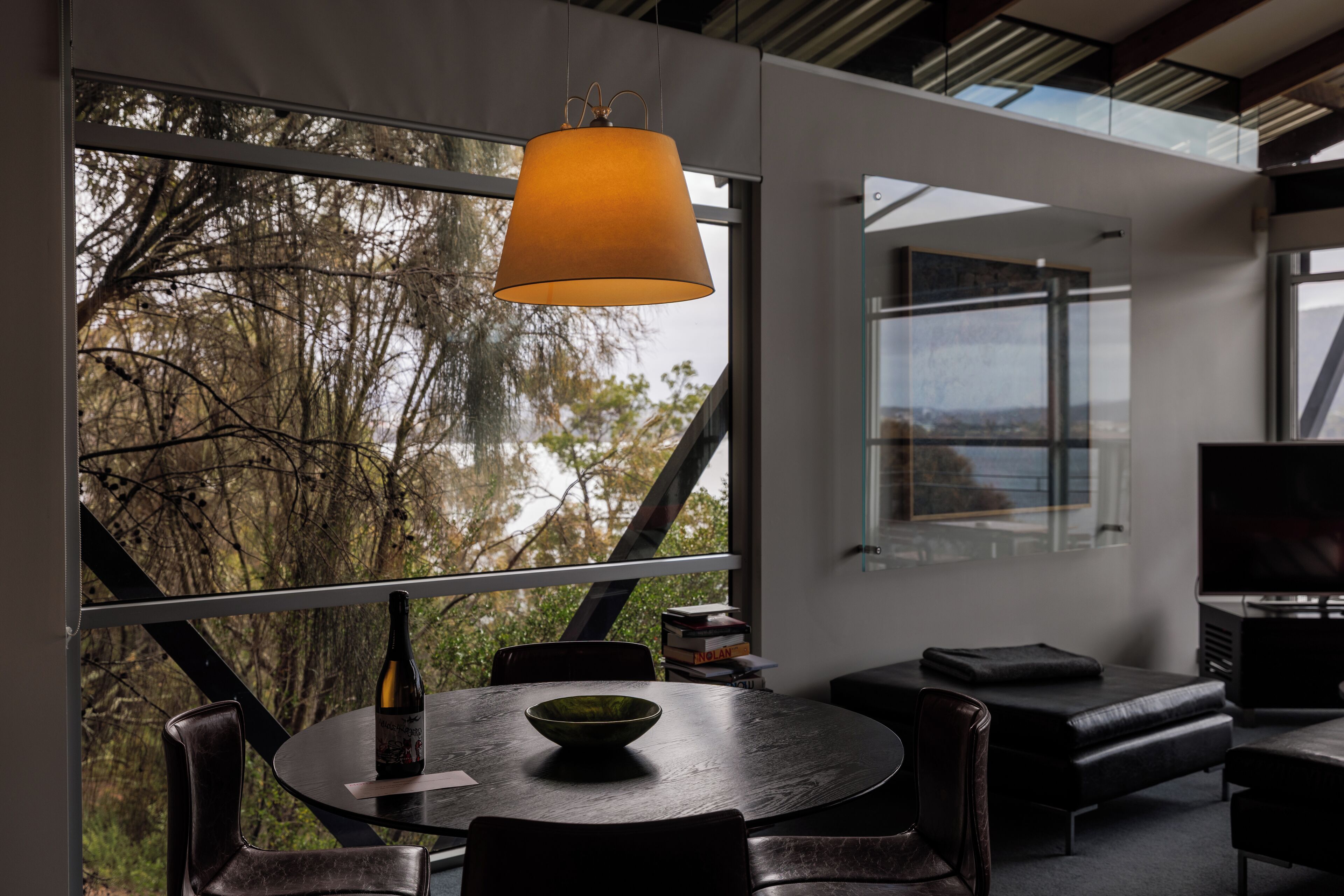 A modern dining area with a round table, chairs, and a hanging lamp.