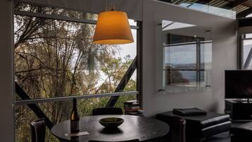 A modern dining area with a round table, chairs, and a hanging lamp.