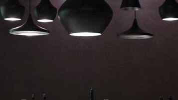 A dining area with multiple pendant lights and a table set with wine bottles and glasses.