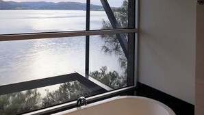 Un bagno con una vasca, un'ampia finestra e vista su un lago.