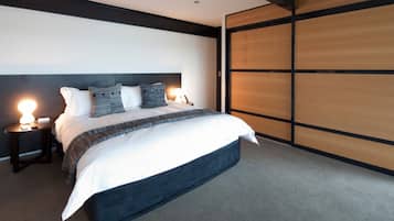 Un dormitorio moderno con una cama grande, cabecera oscura y una puerta corredera de madera.