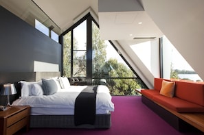 Relax in this serene bedroom with a large bed, a window offering a view of the outdoors, and a comfortable bench for seating.