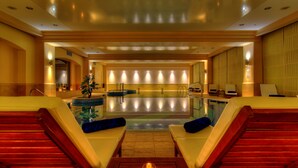 A spa area with a large pool, lounge chairs, and a wooden table with a candle. - Monte Casa Spa & Wellness (Petrovac)