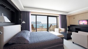 A hotel room with a bed, a TV, a sofa, a small table, and a balcony with a view of the sea. - Monte Casa Spa & Wellness (Petrovac)