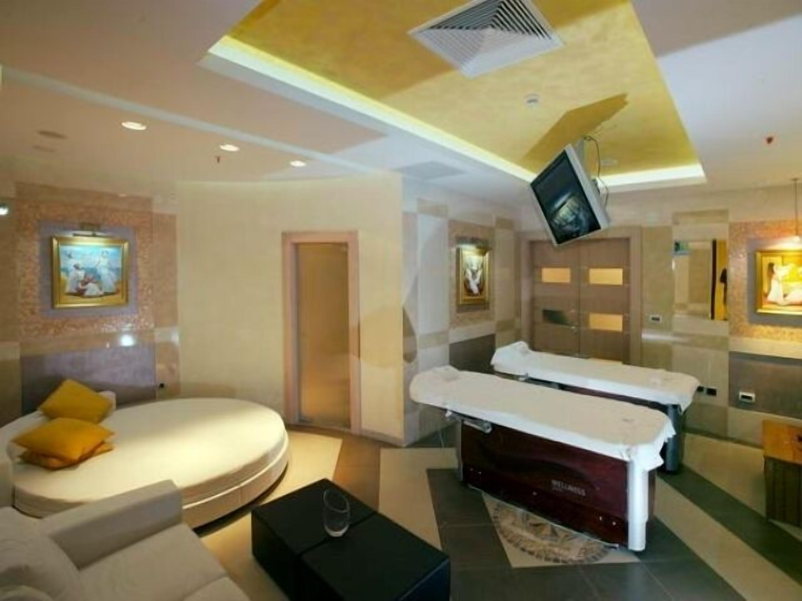 Una habitación de hotel moderna con una cama, una camilla de masaje y un televisor montado en la pared.