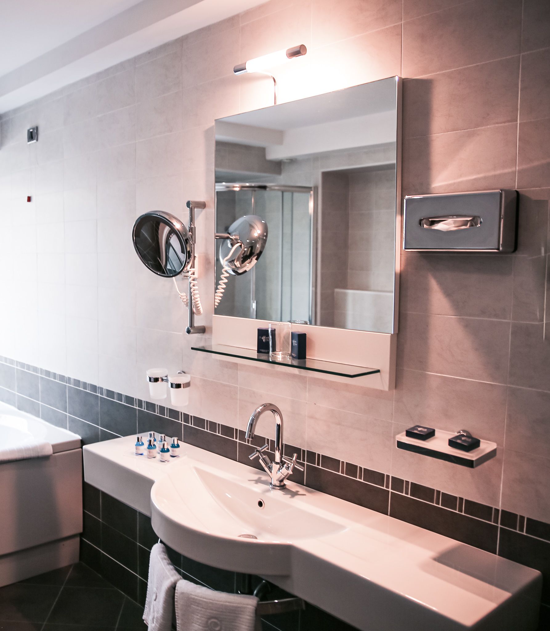 Een moderne badkamer met een grote spiegel, een wastafel en een handdoekhouder.
