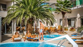 Alberca techada, alberca al aire libre y sombrillas en la alberca