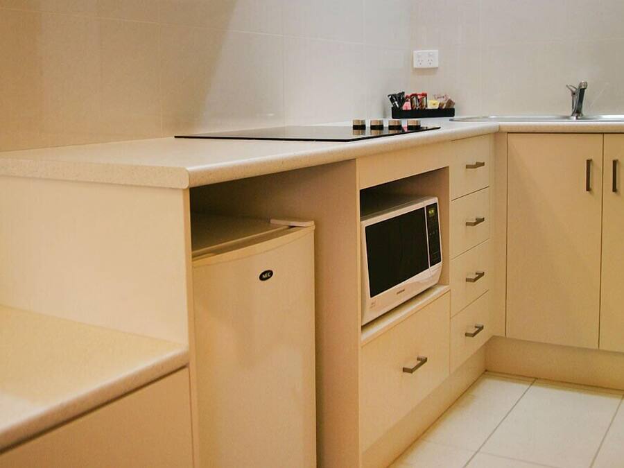 Una cocina compacta con microondas, una pequeña encimera y un armario con cajones.