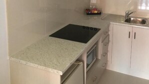 A kitchen with a built-in stove, oven, and a stainless steel range hood. - Footscray Motor Inn (Footscray)