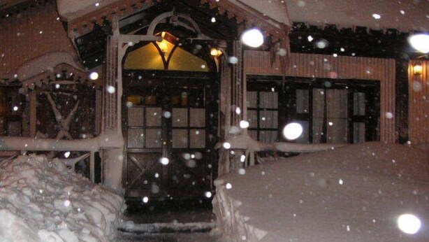 A wooden building with a snow-covered entrance and steps leading up to it. - Campanilla (Ushuaia)