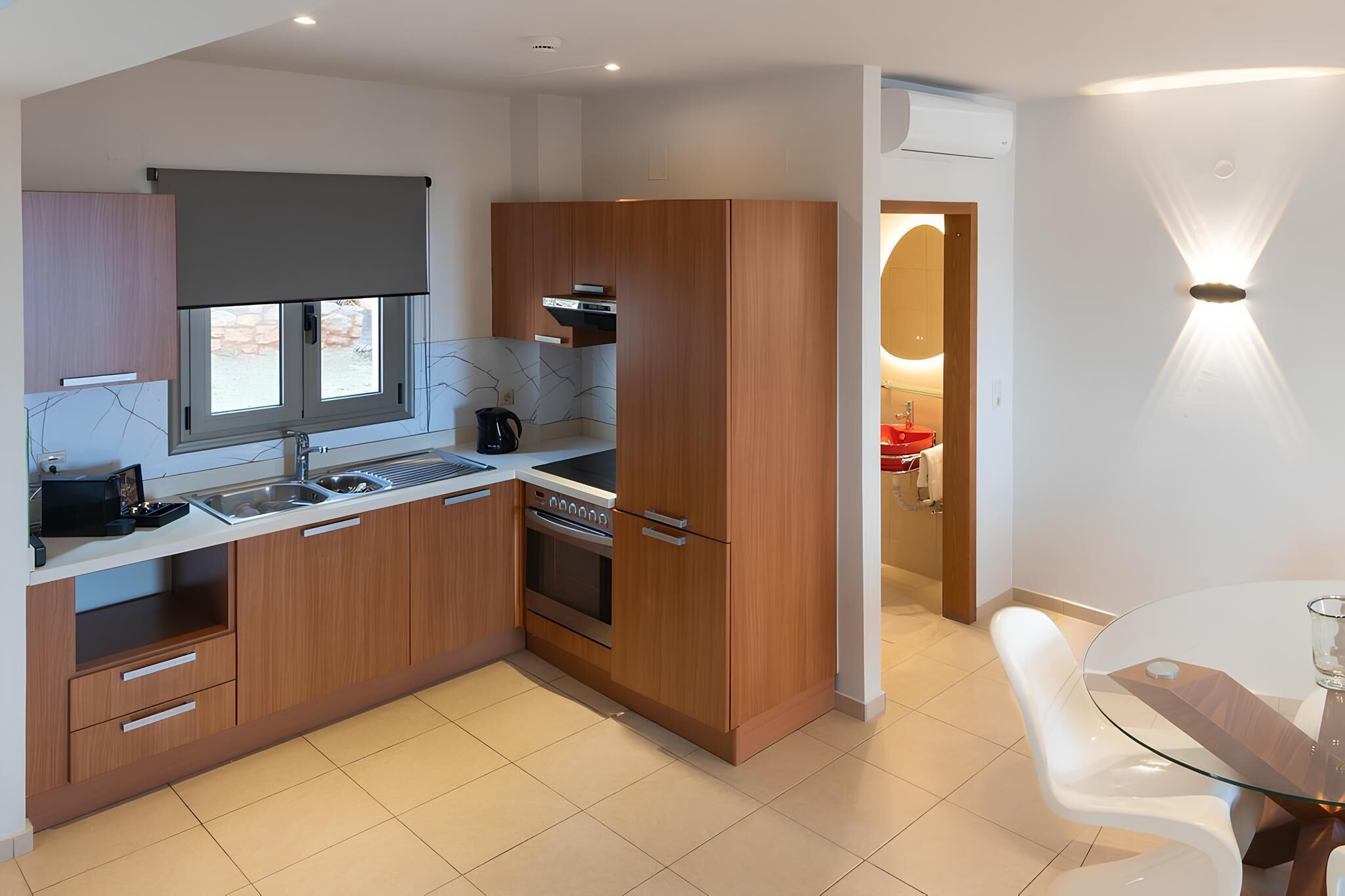 A modern kitchen with wooden cabinets, a built-in oven, and a glass dining table.