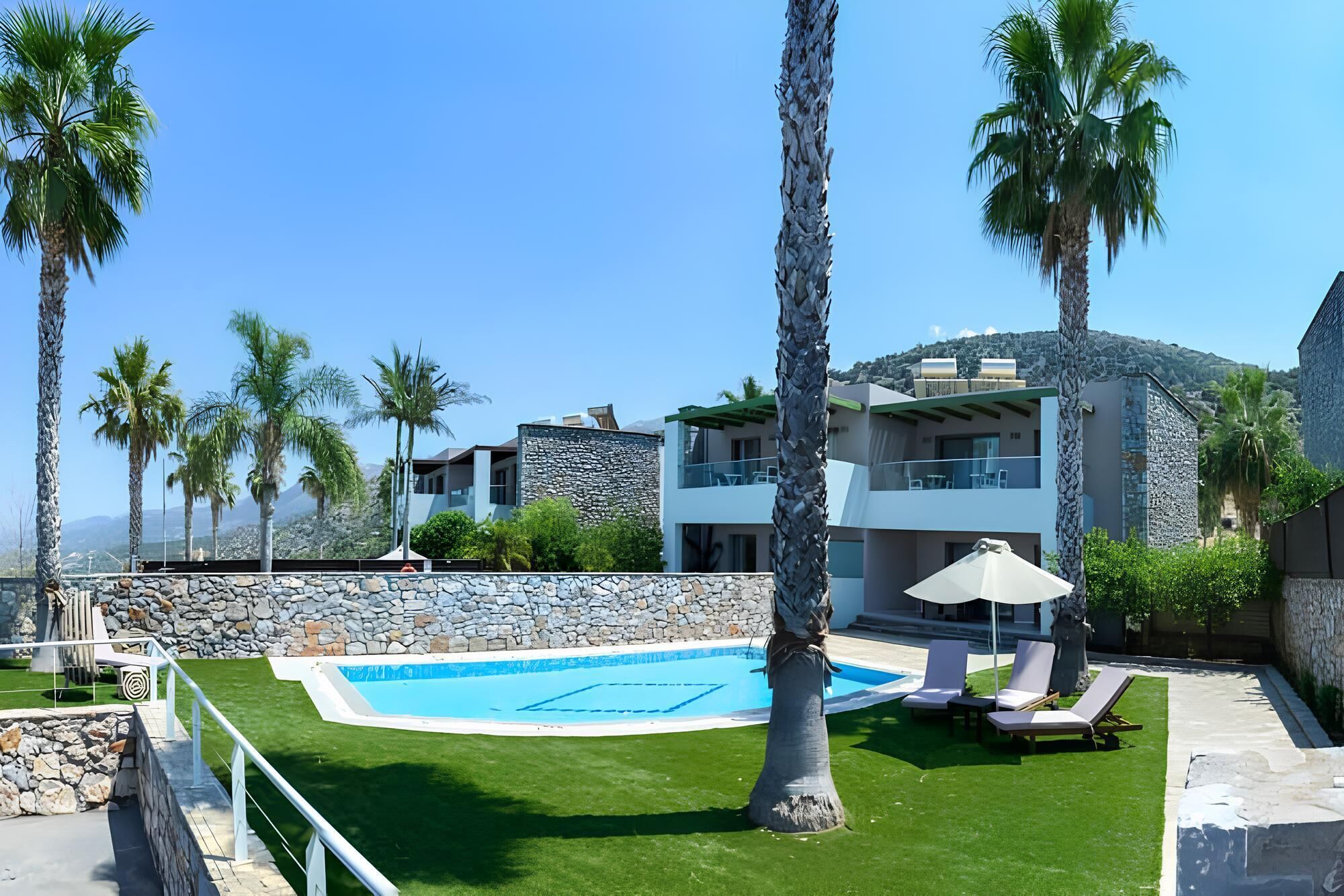 A modern resort with a swimming pool, palm trees, and a view of the mountains.