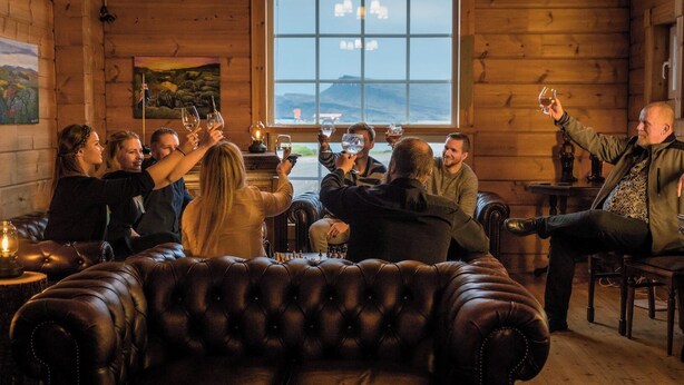 A group of people playing chess in a cozy, wooden room with a large window. - Hotel Breiðdalsvík (Fjardabyggd)