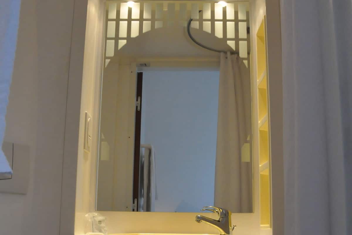 A bathroom with a white toilet, a sink with a mirror above it, and a shower curtain.