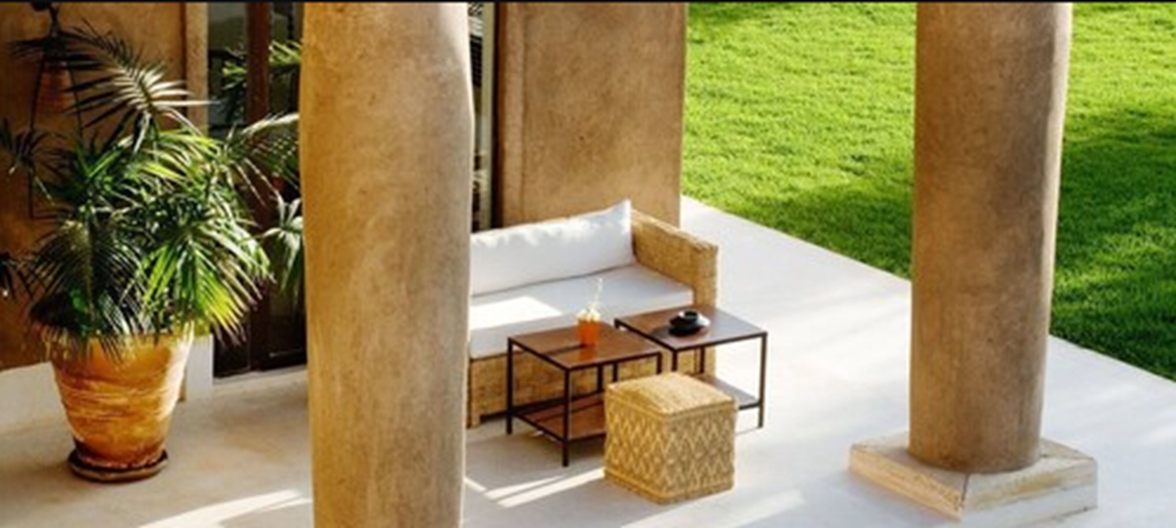 Un espace extérieur moderne aménagé avec un canapé, une petite table et une plante en pot.