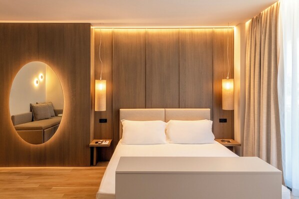 A modern hotel room with a large bed, wooden panel walls, and two bedside lamps. - International Hotel & Suite (San Benedetto del Tronto)