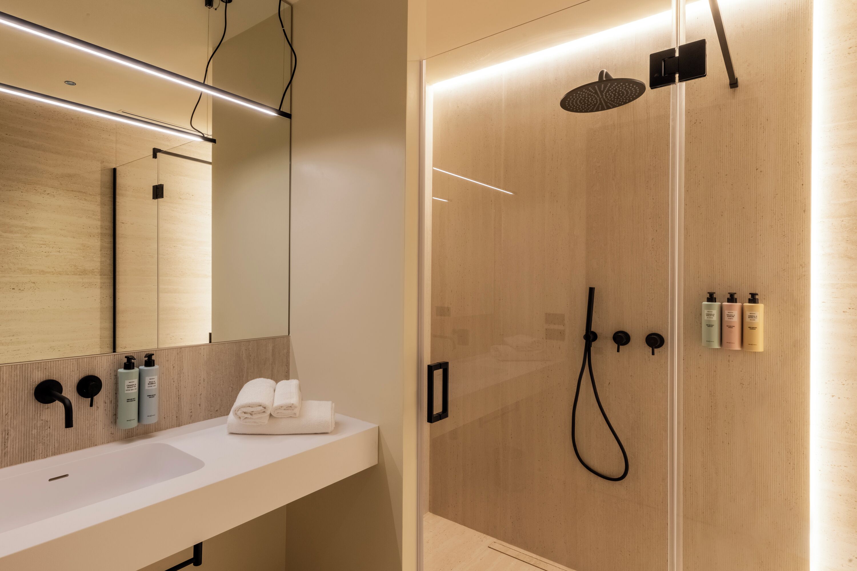 A modern bathroom with a wooden vanity, a large mirror, and a glass-enclosed shower area.