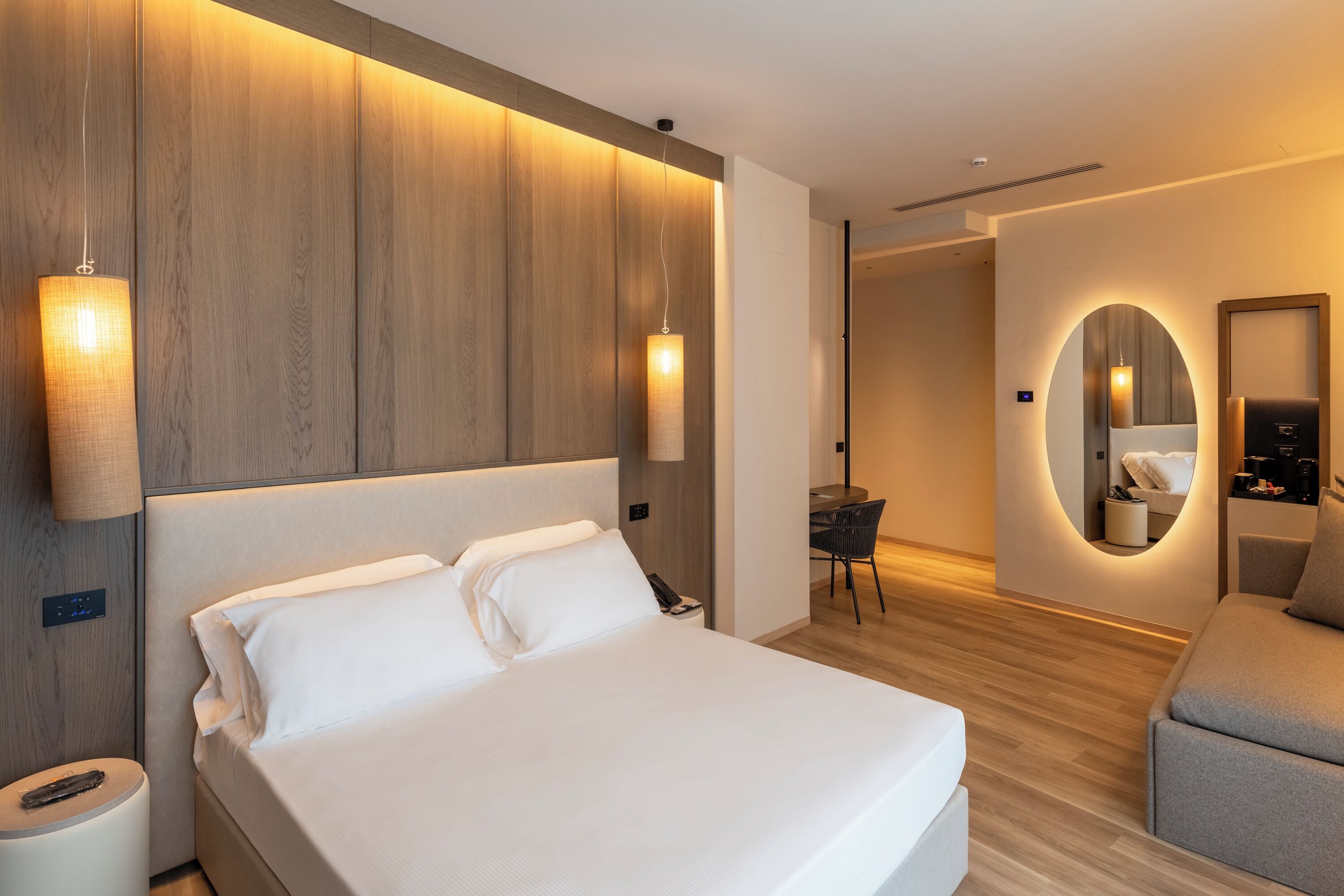 A modern hotel room with a large bed, a desk, and a chair.