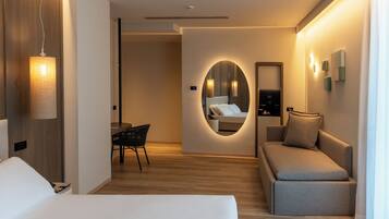 Una habitación de hotel moderna con cama, sofá, escritorio y espejo.