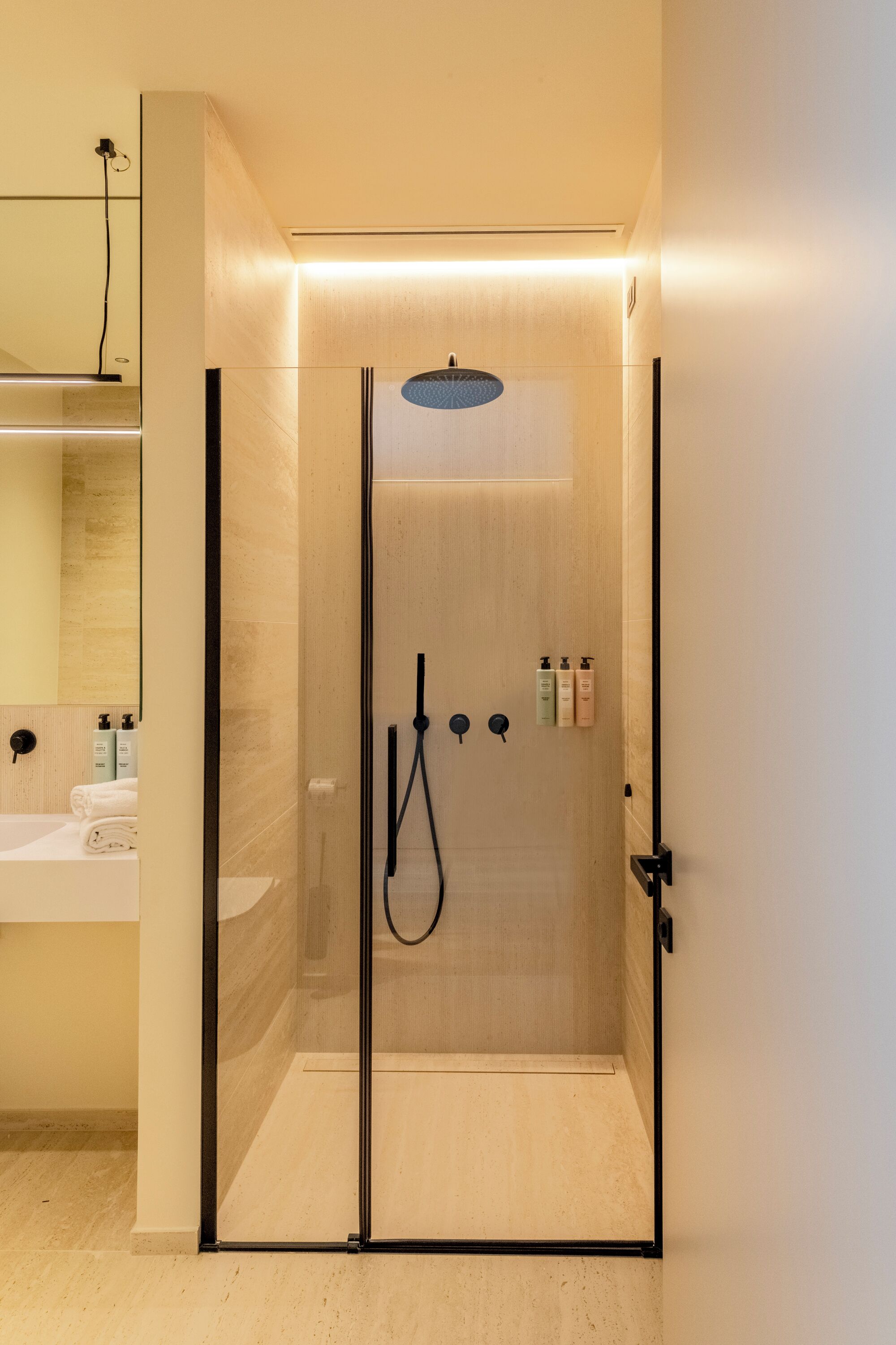 A modern bathroom with a glass-enclosed shower, a sink, and toiletries.