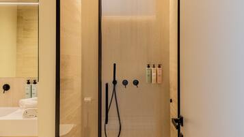 Un baño moderno con ducha de vidrio, lavamanos y artículos de aseo.