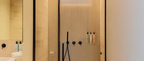 A modern bathroom with a glass-enclosed shower, a sink, and toiletries.