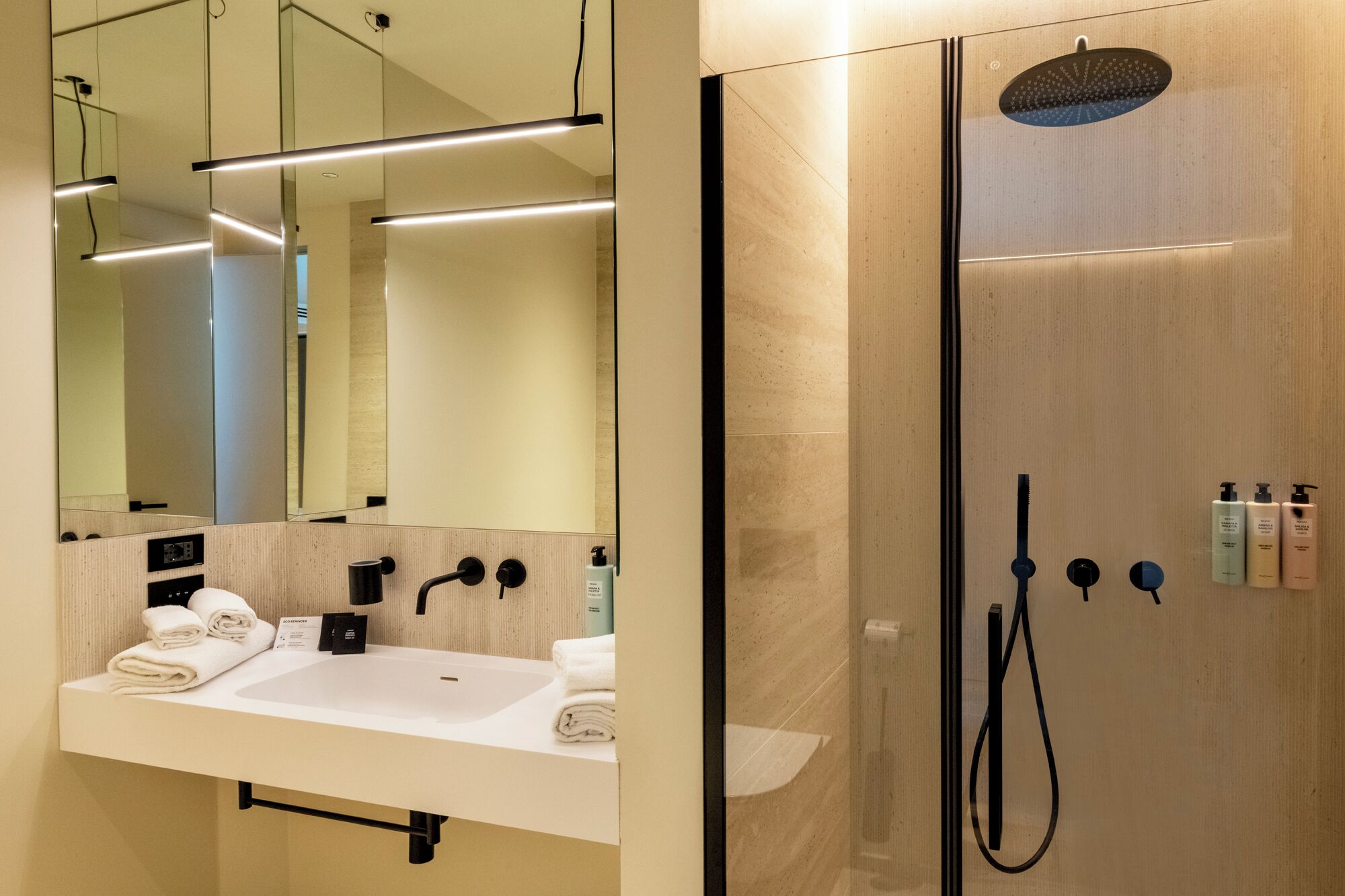 Ein modernes Badezimmer mit großem Spiegel, Waschbecken und Duschbereich.