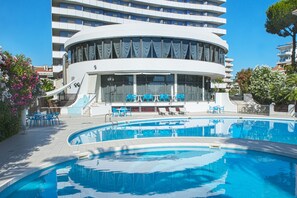 A modern hotel with a pool area, including lounge chairs and a sun terrace.