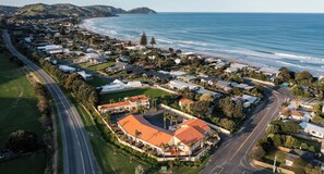 An aerial view of a coastal residential area with houses, a main road, and a beach. - Ocean Beach Wainui (Gisborne)