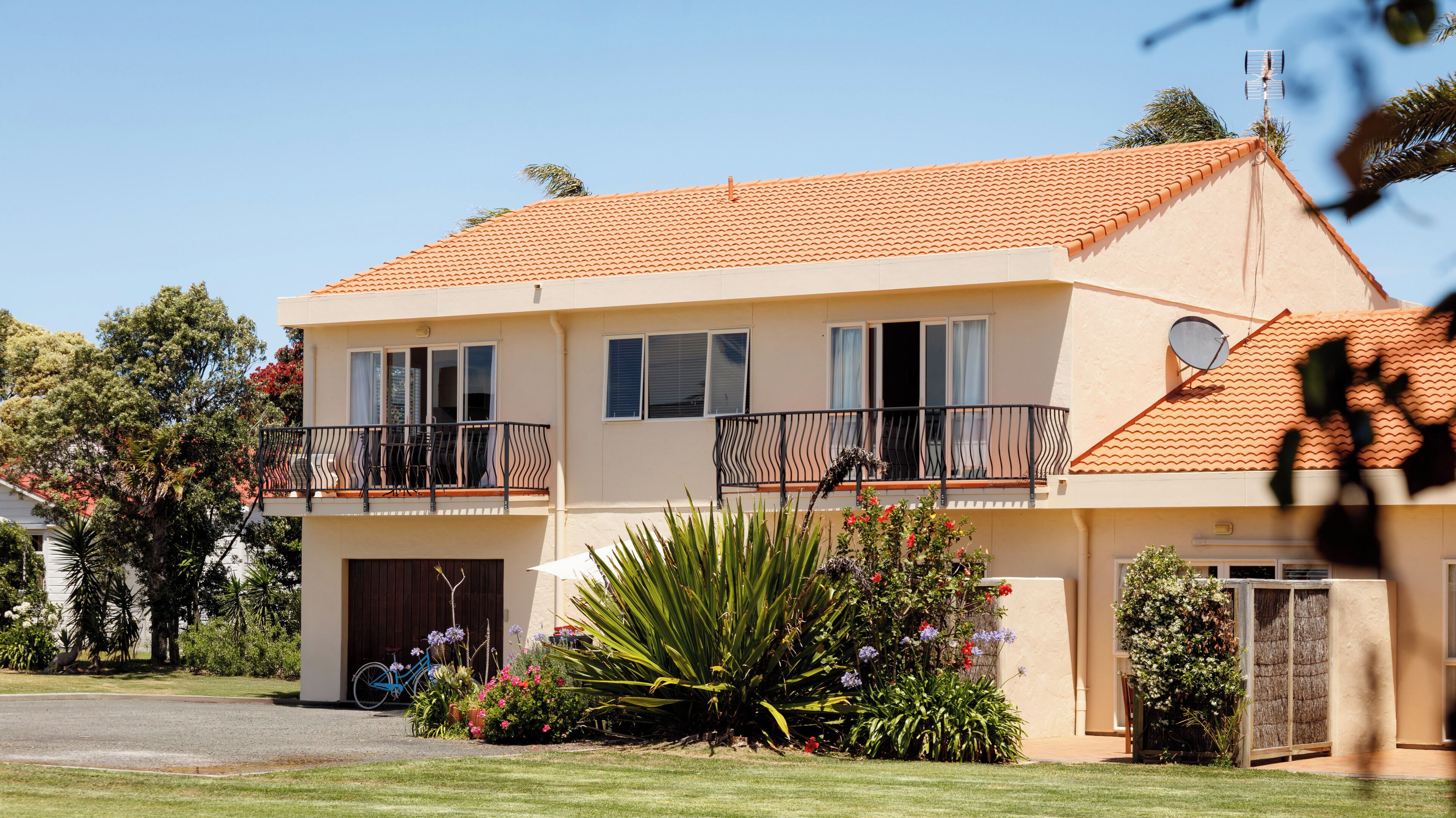 A two-story house with a balcony, a garage, and a well-maintained garden.