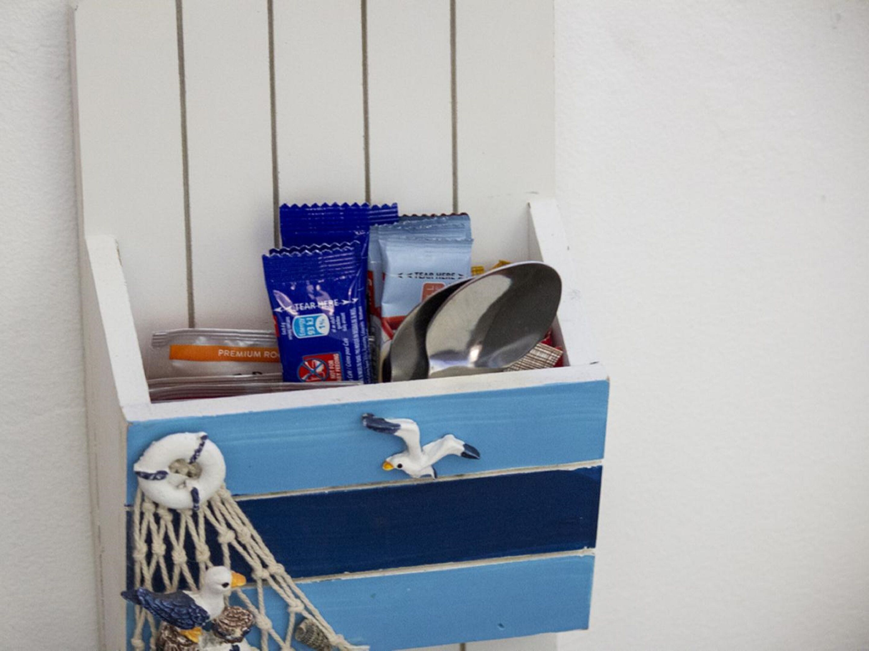 Eine blaue Aufbewahrungsbox mit Fächern, die einen Metallsöhn, eine blaue Packung und einen weißen Behälter enthält.