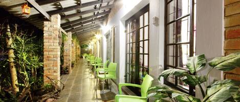 A corridor with green chairs, brick walls, and large windows.