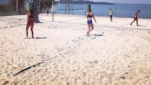 Una playa arenosa con una red de voleibol y jugadores.
