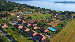 An aerial view of a residential area with houses, a swimming pool, and a lake in the background. - Le Tre Isole (Magione)