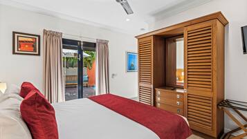 Ein Schlafzimmer mit Bett, einem Holzschrank, einem Deckenventilator und Blick ins Freie.