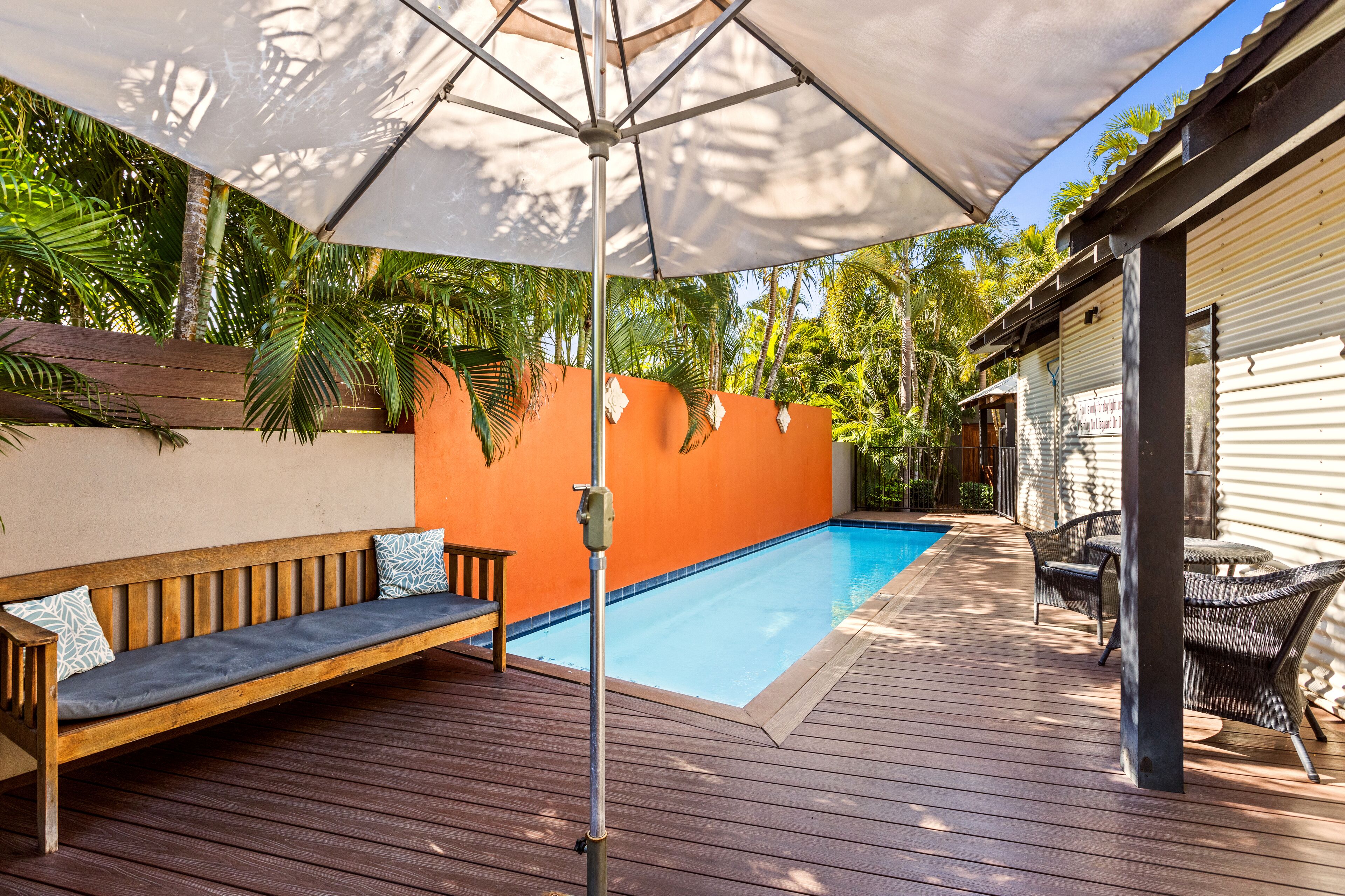A wooden deck with a pool, a bench, and outdoor furniture.