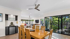 A modern kitchen with a dishwasher, a dining area with a wooden table and chairs, and a large sliding glass door leading to a garden.