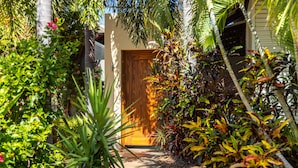 A pathway leading to a wooden door surrounded by lush tropical plants.