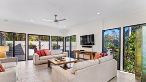 A spacious living room with a sofa set, a coffee table, and a TV mounted on the wall.