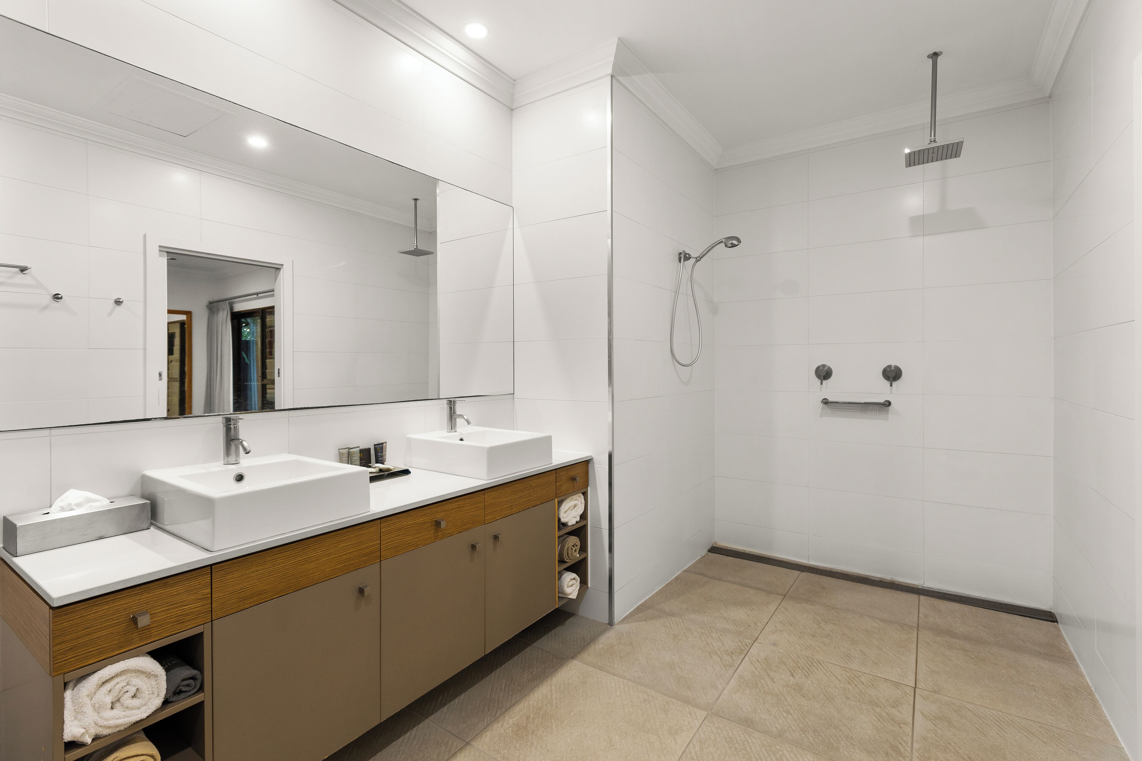 Een moderne badkamer met twee wastafels, een grote spiegel en een douchegedeelte.