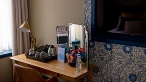 Une chambre d’hôtel avec un bureau en bois, un miroir, une lampe et un téléviseur.