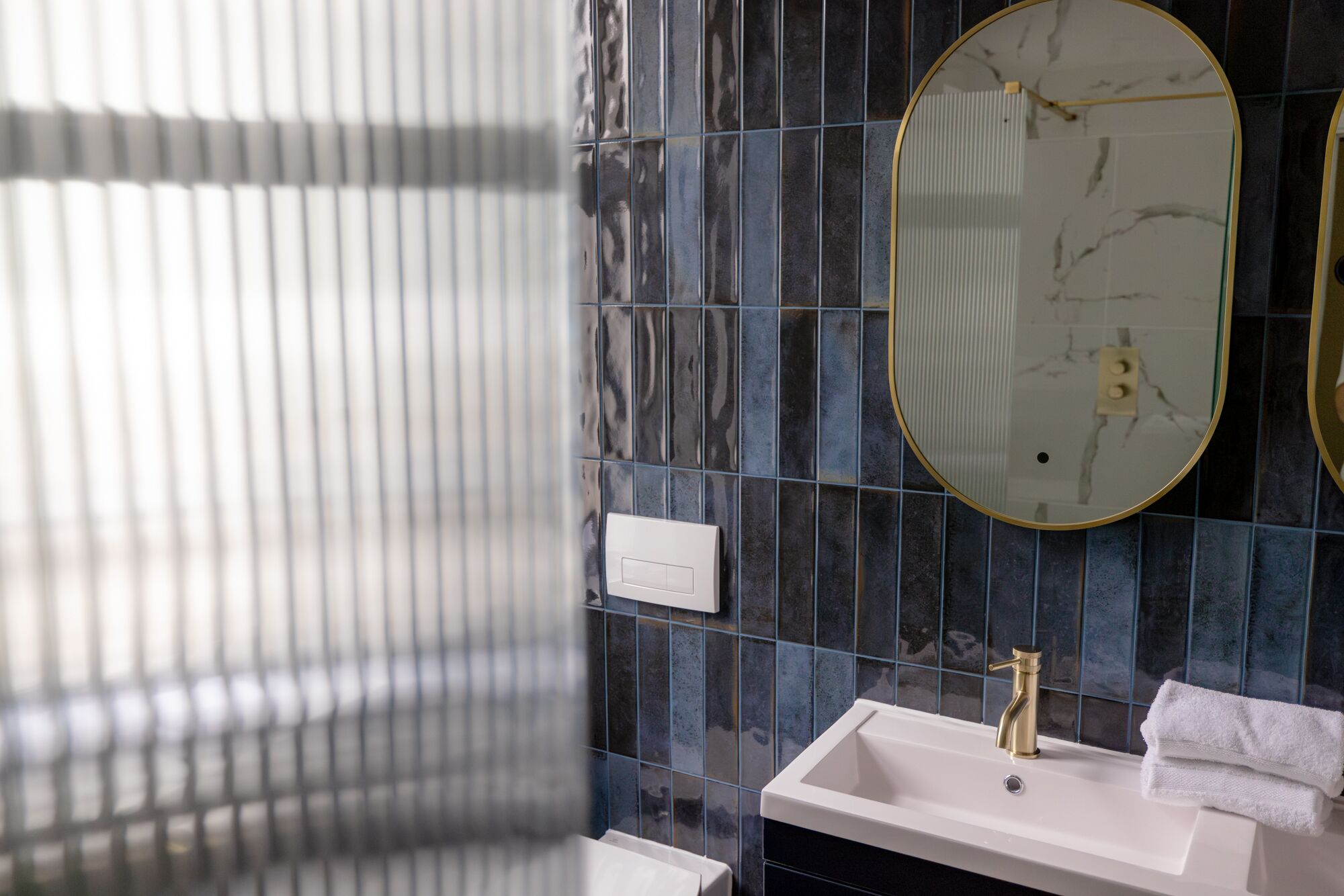 A bathroom with a white sink, a gold faucet, and a mirror with a gold frame.