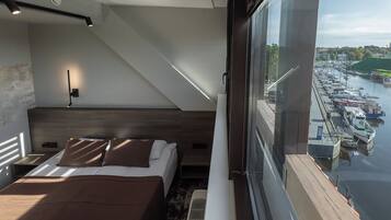 A modern bedroom with a bed, bedside table, and a view of a marina.