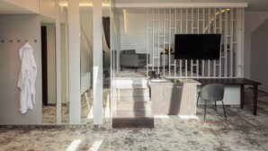 A modern interior with a kitchen area, a dining table, and a flat-screen TV mounted on a white partition. - Old Mill Hotel (Klaipeda)