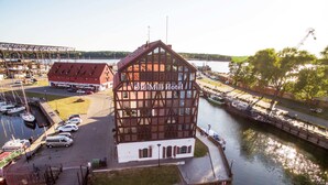 A hotel with a distinctive timber-framed structure, situated by a waterway with boats docked nearby. - Old Mill Hotel (Klaipeda)
